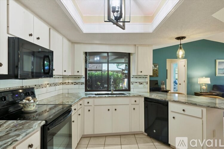 A kitchen with black and white appliances and a marble countertop.