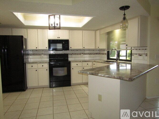 A kitchen with black appliances and white cabinets.