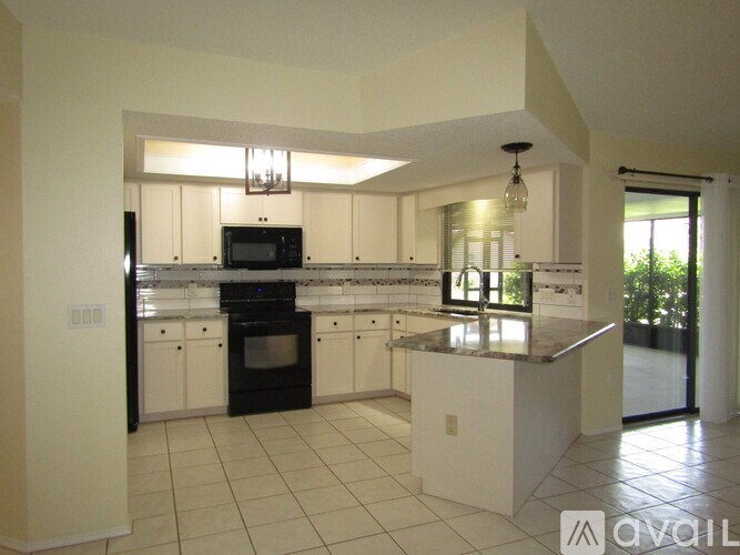 A modern kitchen with white cabinets and black appliances.