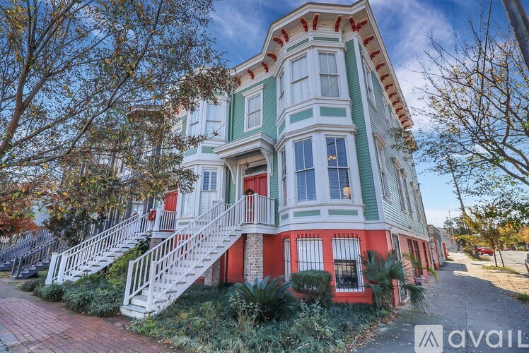 A two-story house with a red and green exterior and white railings.