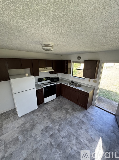 A kitchen with white appliances and a tile floor.
