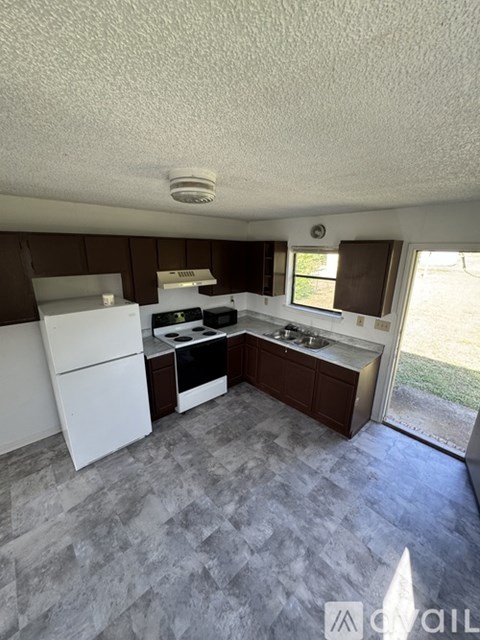 A kitchen with white appliances and a tile floor.