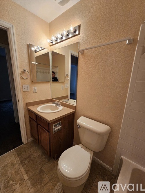 A bathroom with a toilet, sink, mirror and lights.