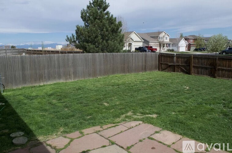 A backyard with a wooden fence and a brick patio.