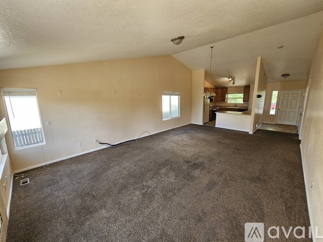 A spacious room with carpeted floor and a window on the left side.
