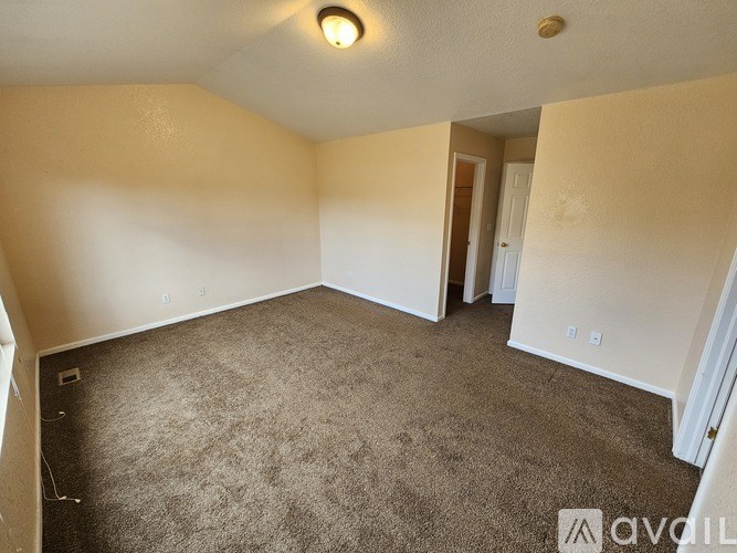 A carpeted room with a doorway leading to another room.