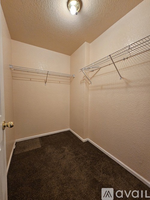 A small, empty room with a carpeted floor and a door on the left.