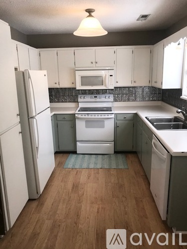 A kitchen with white appliances and wooden floors.