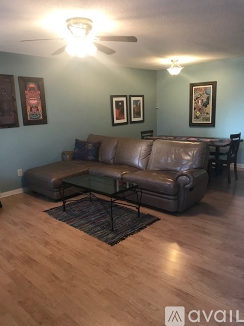 A living room with a brown leather couch and a glass coffee table.
