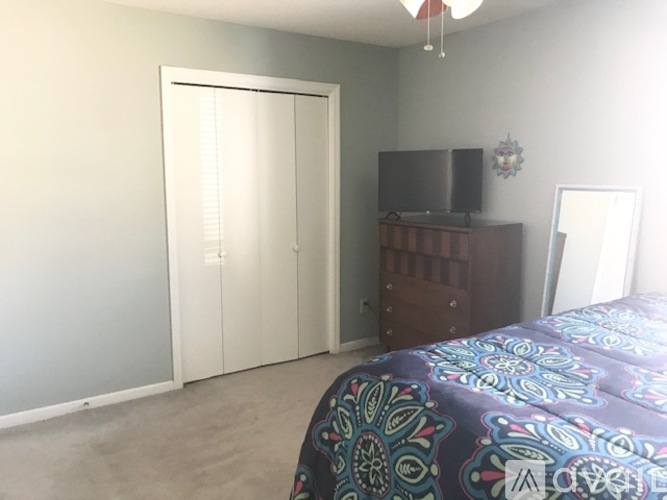 A bedroom with a bed, dresser, and television.
