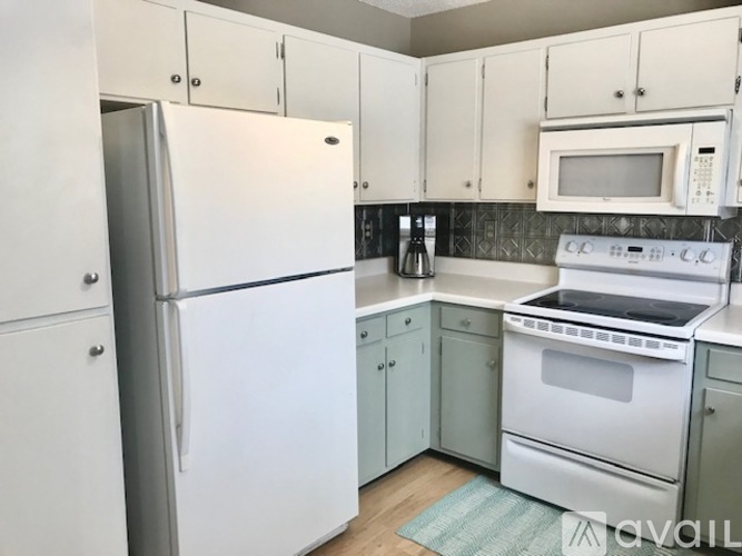 A kitchen with white appliances and cabinets.