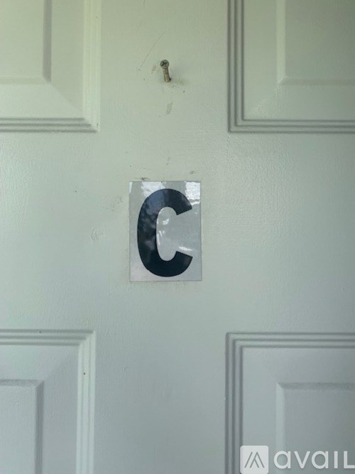 A white door with a black letter c on the wall.