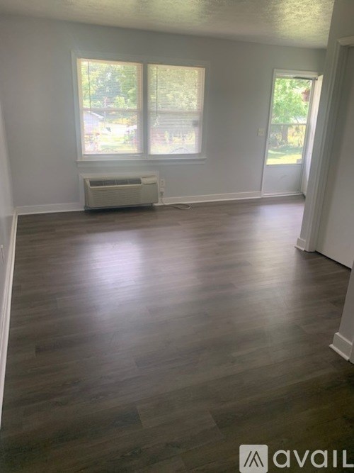 A room with wooden flooring and a window with blinds.