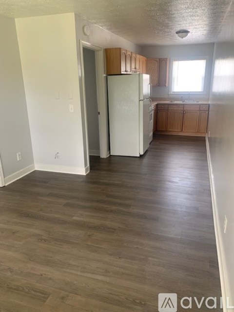 A kitchen with a white refrigerator and wooden cabinets.