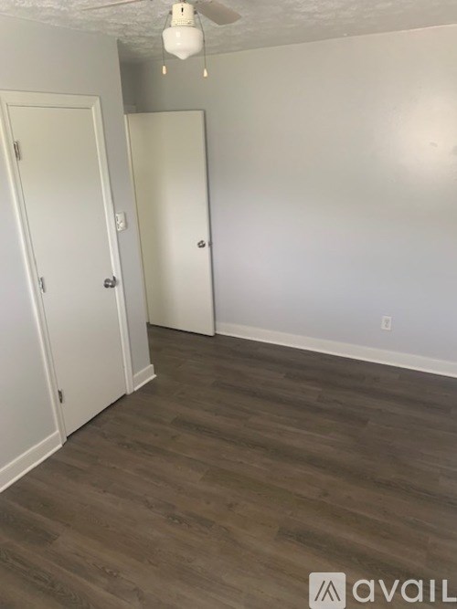 A room with wooden flooring and two white doors.