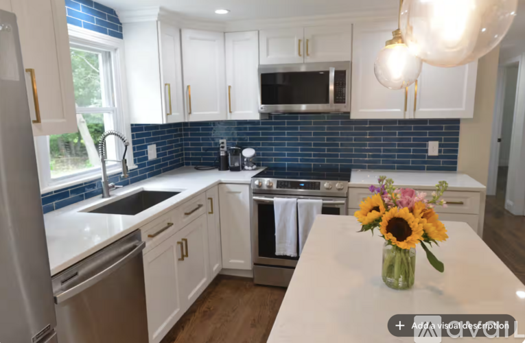 A kitchen with white cabinets and a blue backsplash.