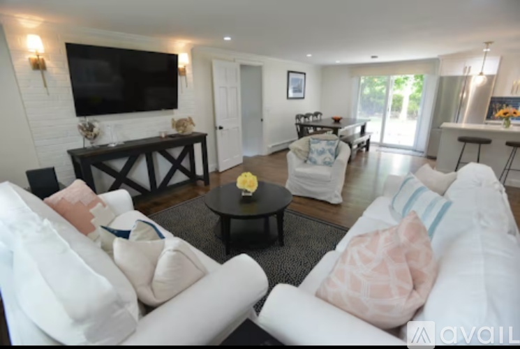 A living room with a white couch and a flat screen TV mounted on the wall.