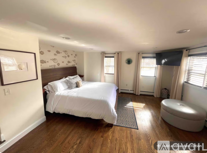 A bedroom with a large bed and a round ottoman.