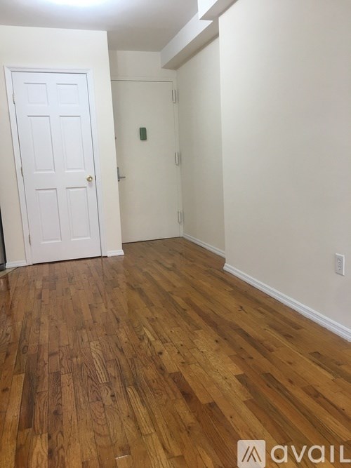 A room with a white door and wooden flooring.