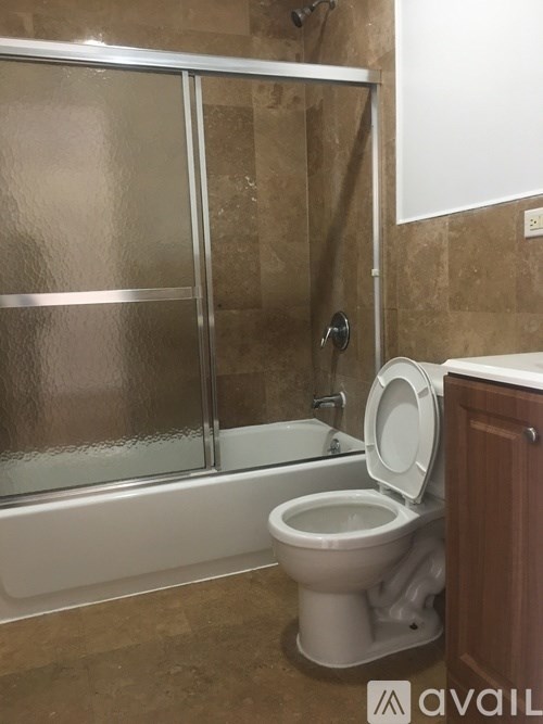 A white toilet is in a bathroom with a glass shower door.