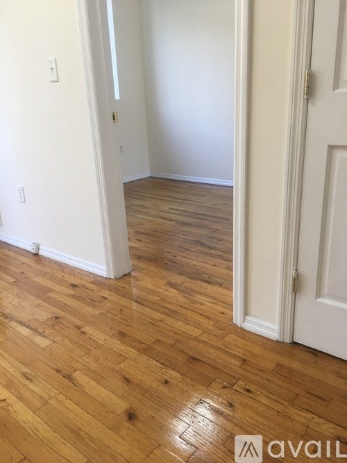 A room with a white door and a wooden floor.