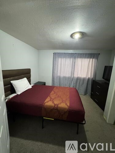 A bedroom with a bed, nightstand, and dresser.