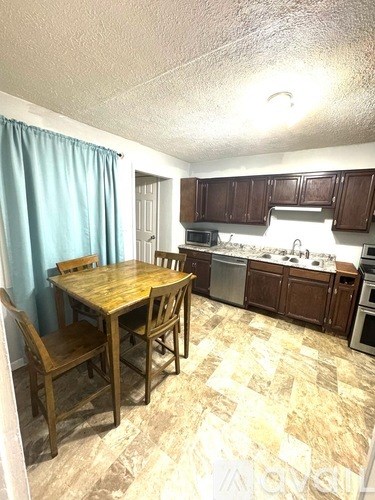 A kitchen with a table and chairs in front of it.