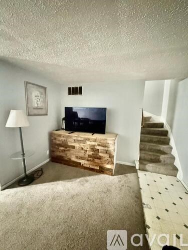 A living room with a television and stairs.