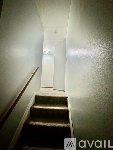 A narrow hallway with a staircase leading to a door at the end.