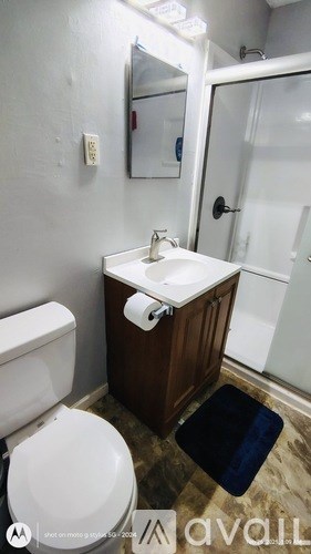 A bathroom with a toilet, sink, and mirror.