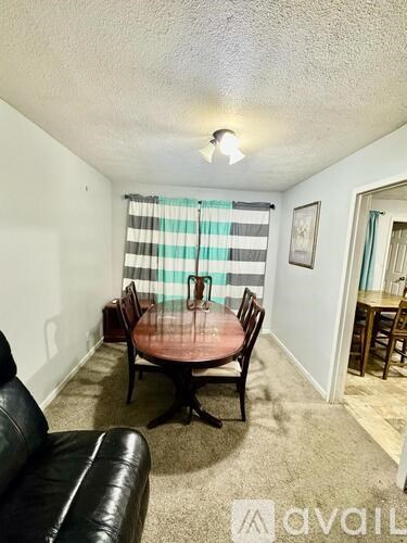 A living room with a black leather couch and a round wooden table.