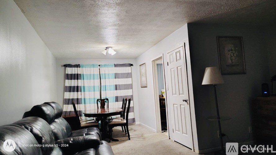 A living room with a black leather couch and a checkered curtain.