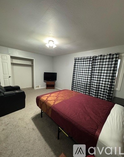 A bedroom with a bed, couch, and television.