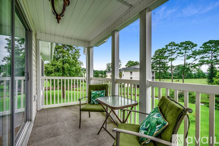 A patio with a table and chairs overlooking a grassy area.