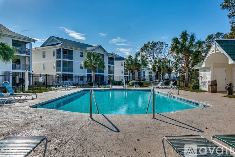 A pool surrounded by chairs and apartment buildings.