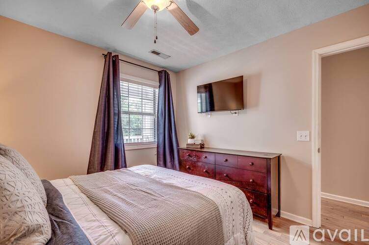 A bedroom with a bed, dresser, and window.
