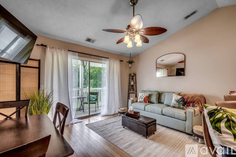 A living room with a couch, a coffee table, and a ceiling fan.