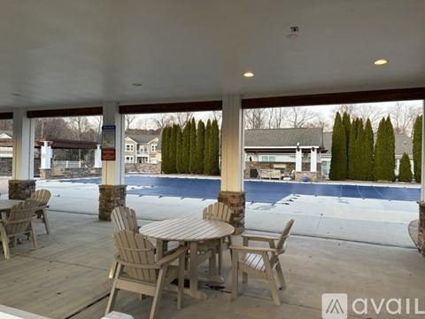 A patio with a table and chairs overlooking a pool.