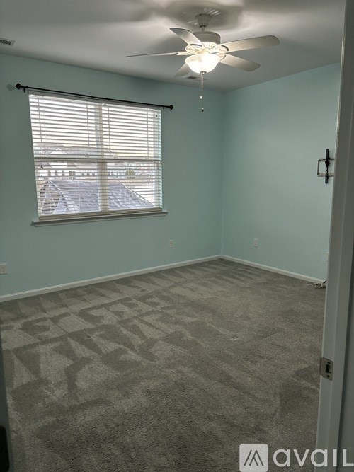 A room with a carpeted floor and a ceiling fan.