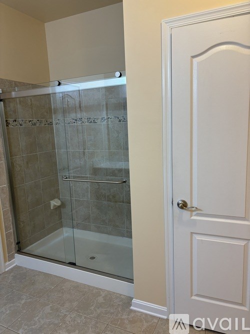 A bathroom with a glass shower door and a white door.