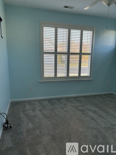 A room with a window covered by white blinds.