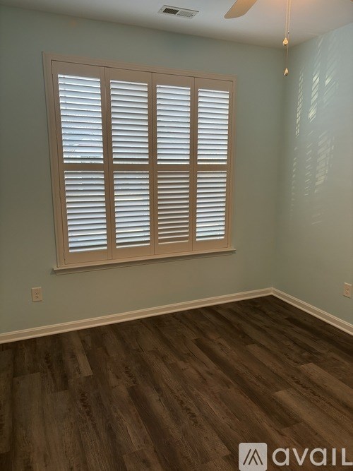 A room with wooden flooring and a window with shutters.