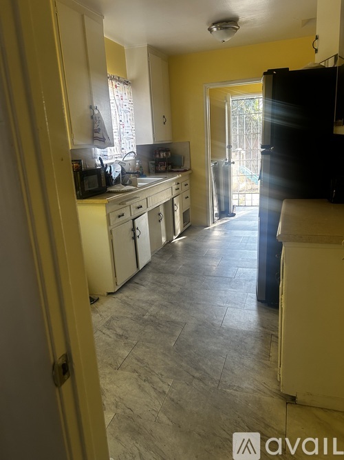 A kitchen with yellow walls and a black fridge.