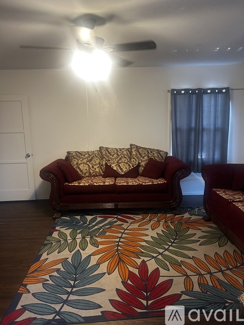 A living room with a red couch and a colorful rug.