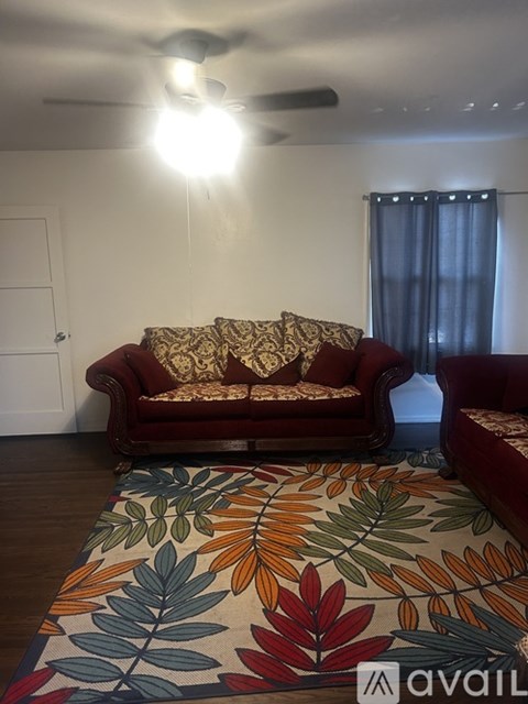 A living room with a red couch and a colorful rug.
