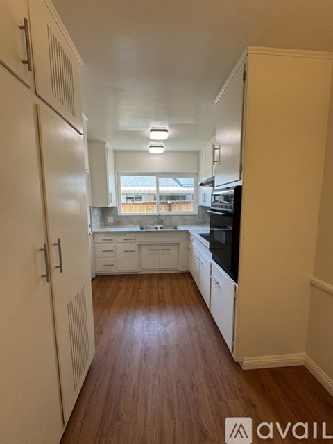 A kitchen with white cabinets and a black countertop.