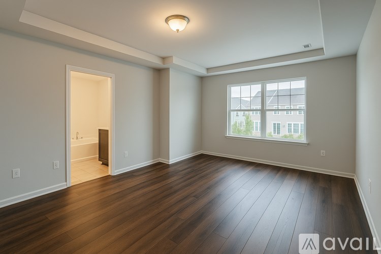 A spacious room with wooden flooring and a large window.