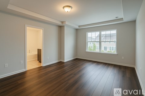 A spacious room with wooden flooring and a large window.