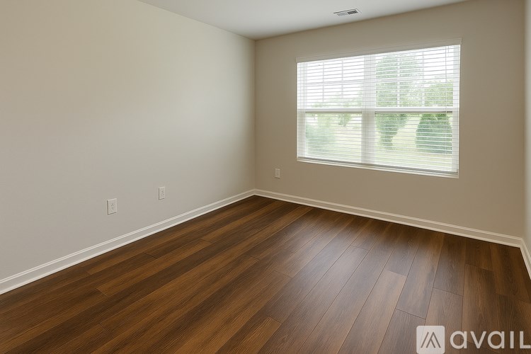 A room with wooden flooring and a window with blinds.