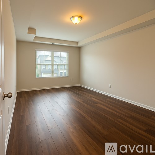 A room with a light hanging from the ceiling and a black bin on the floor.